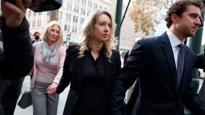 Holmes (no centro) junto com o marido e a mãe dela enquanto entravam no tribunal