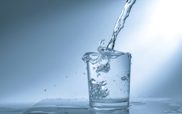 pouring-water-into-glass-973900808-5c7d4ecac9e77c0001f57c7a Descubra se beber dois litros de água por dia é realmente necessário. Saiba como calcular sua necessidade de hidratação com base em fatores individuais.