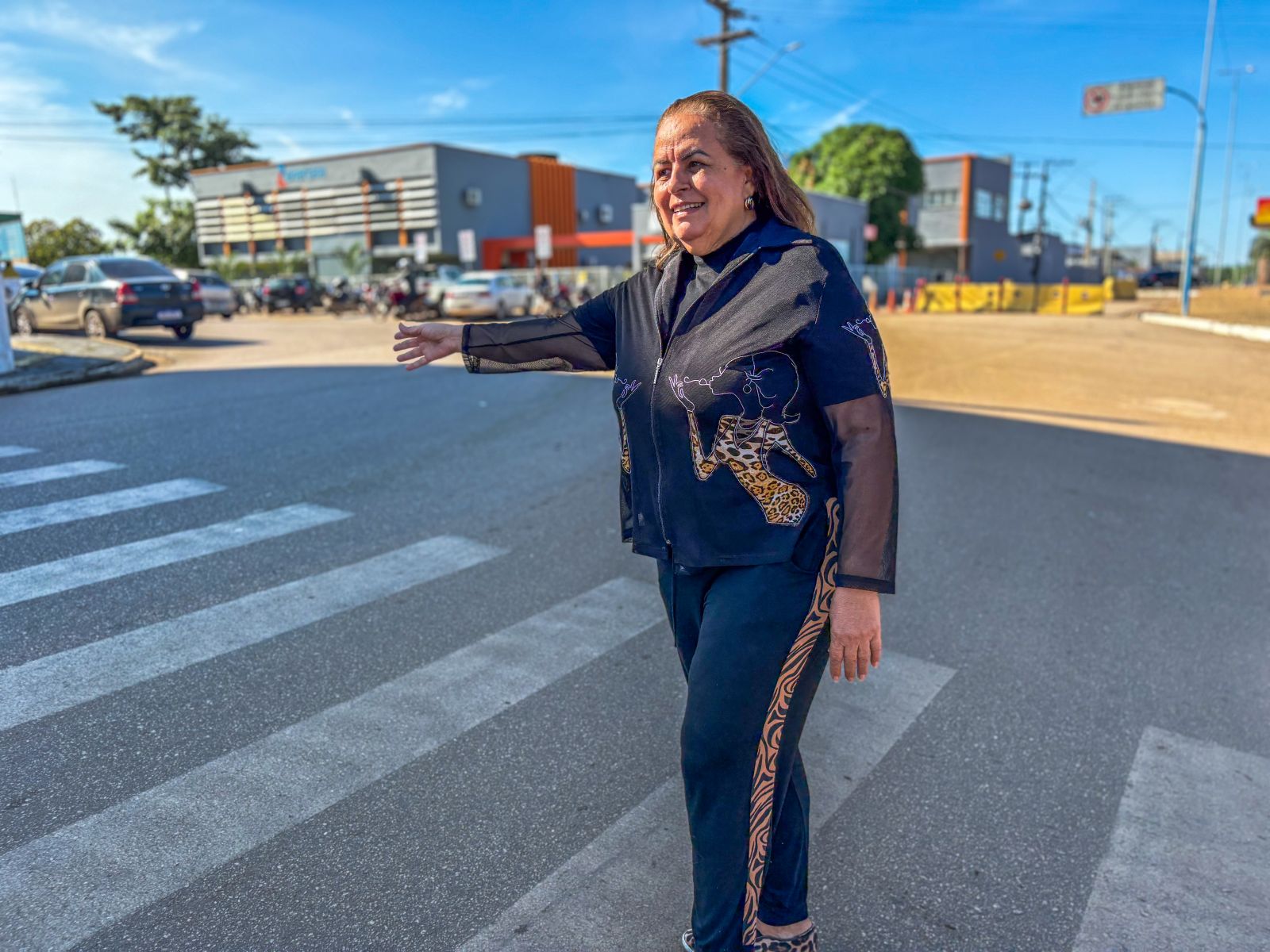 Mulher realiza o gesto do sinal de vida antes de atravessar faixa de pedestres em rua movimentada