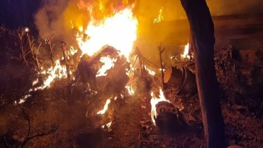  Destroços de aeronave em chamas após explosão noturna, com fogo intenso consumindo os escombros