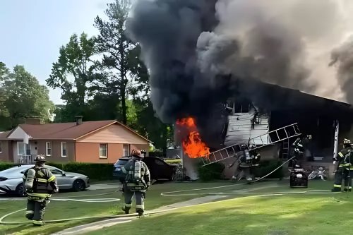 Casa em chamas com fumaça densa saindo do telhado durante incêndio residencial em área urbana