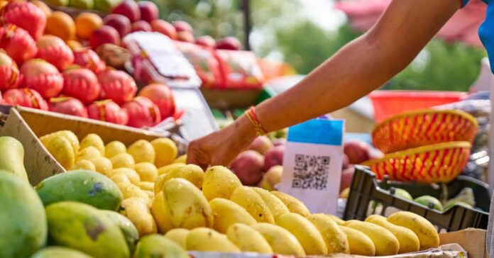 Consumidoras analisam frutas e verduras com preços promocionais em mercado popular