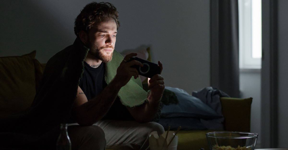  Adolescente usando o celular sozinho em quarto escuro, ilustrando os efeitos do isolamento digital