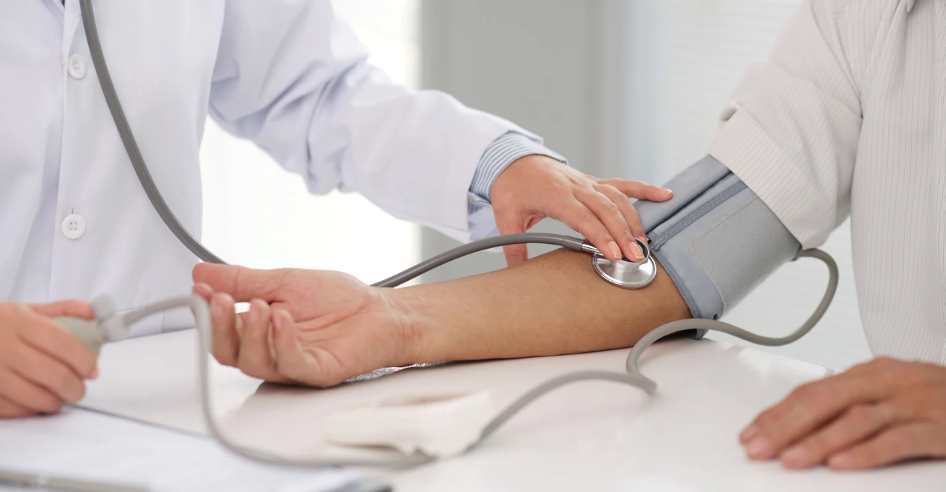 Profissional de saúde mede a pressão arterial de paciente com estetoscópio e esfigmomanômetro.