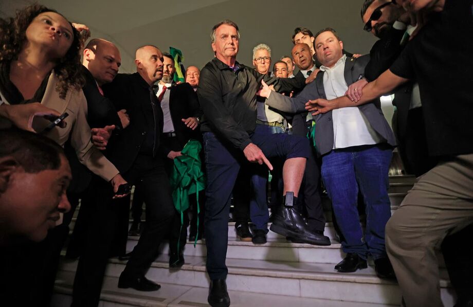 Jair Bolsonaro exibe tornozeleira eletrônica durante visita à Câmara dos Deputados, cercado por apoiadores e parlamentares.
