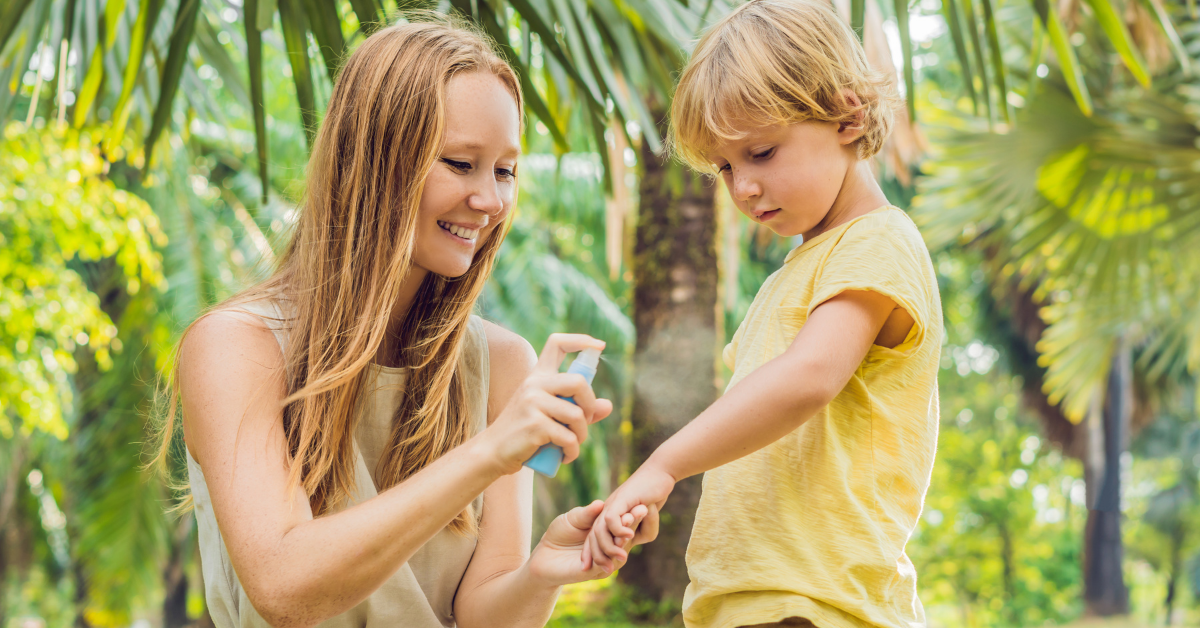 Mulher aplica repelente no braço de uma criança em área verde, simbolizando proteção prolongada contra o mosquito da dengue
