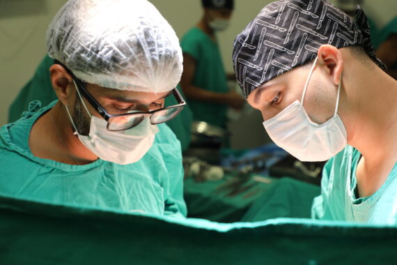  Imagem mostra cirurgiões em operação sob luz intensa, representando a eficiência e estrutura do Hospital de Retaguarda em Rondônia.