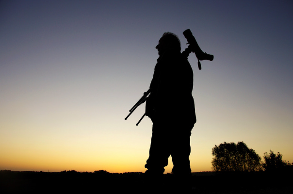 Silhueta de homem com tripé e telescópio ao pôr do sol, preparando-se para observar o céu
