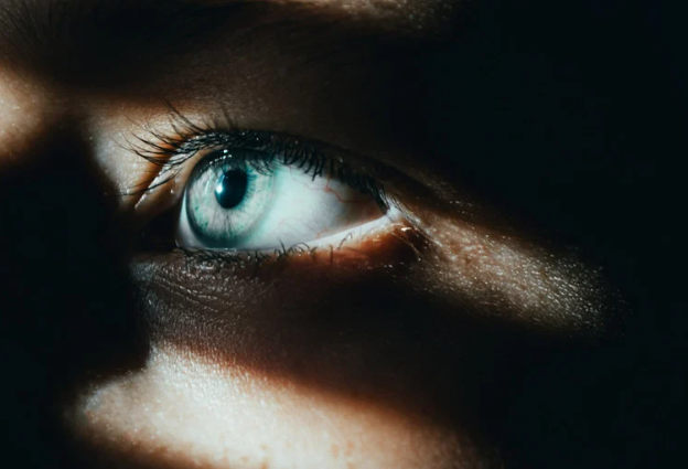 Close de um olho azul com feixe de luz iluminando a retina