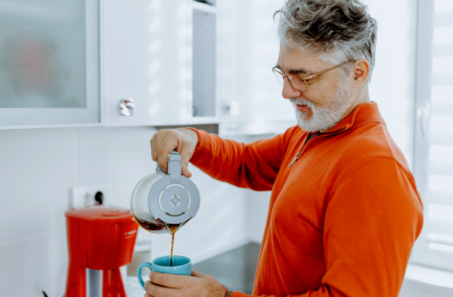 Homem maduro servindo café preto sem açúcar em uma caneca azul