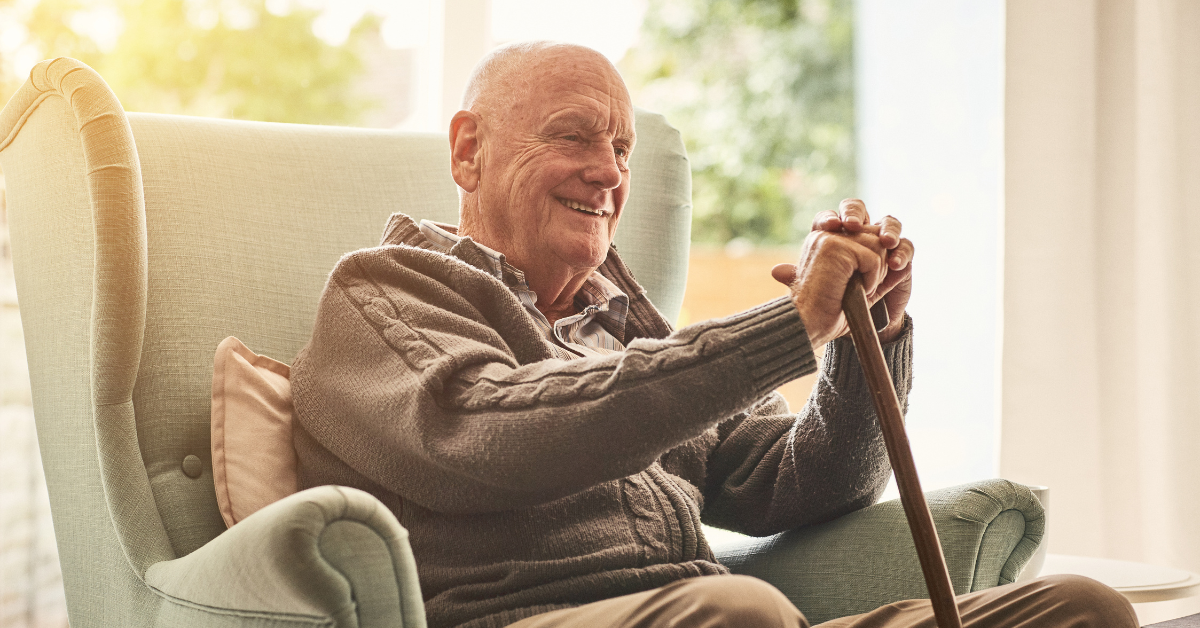 Idoso sorridente sentado em poltrona em ambiente iluminado