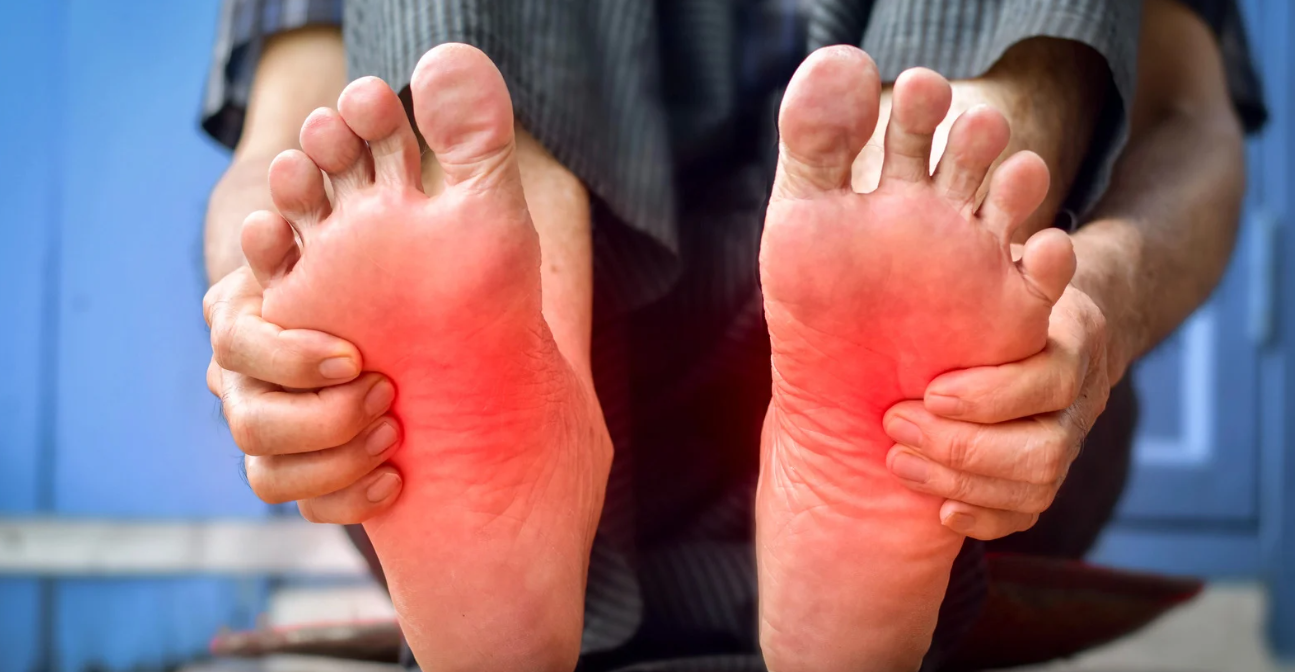 Pessoa segurando os pés com vermelhidão, indicando dormência nas extremidades