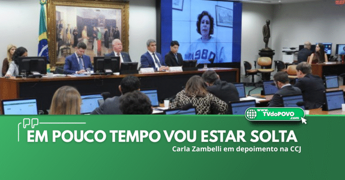 Deputada Carla Zambelli aparece em telão durante depoimento remoto à CCJ da Câmara dos Deputados, com parlamentares acompanhando a sessão.