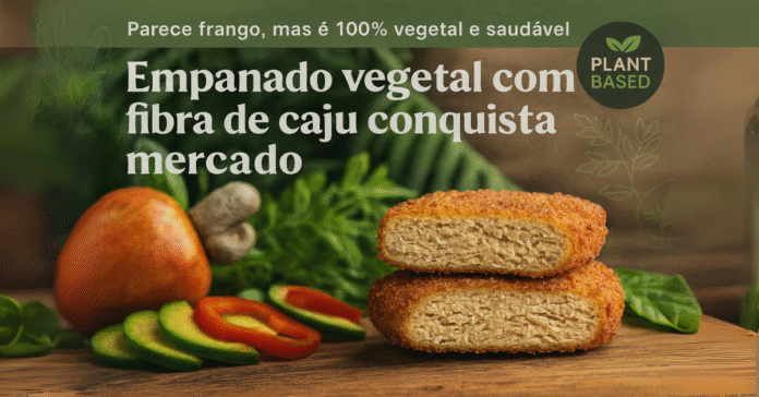 Empanado vegetal com fibra de caju cortado ao meio, ao lado de caju e legumes frescos, sobre superfície de madeira