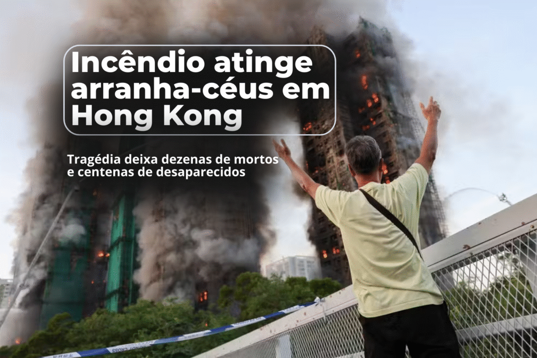 Homem levanta os braços enquanto arranha-céus em Hong Kong são consumidos por um incêndio de grande proporção.